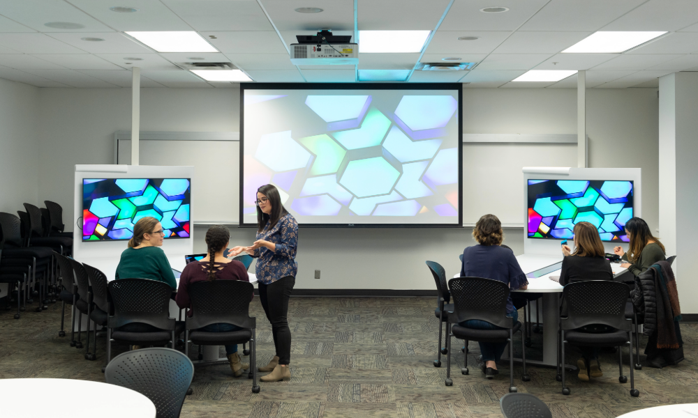 Students in classroom with screens and projector on.