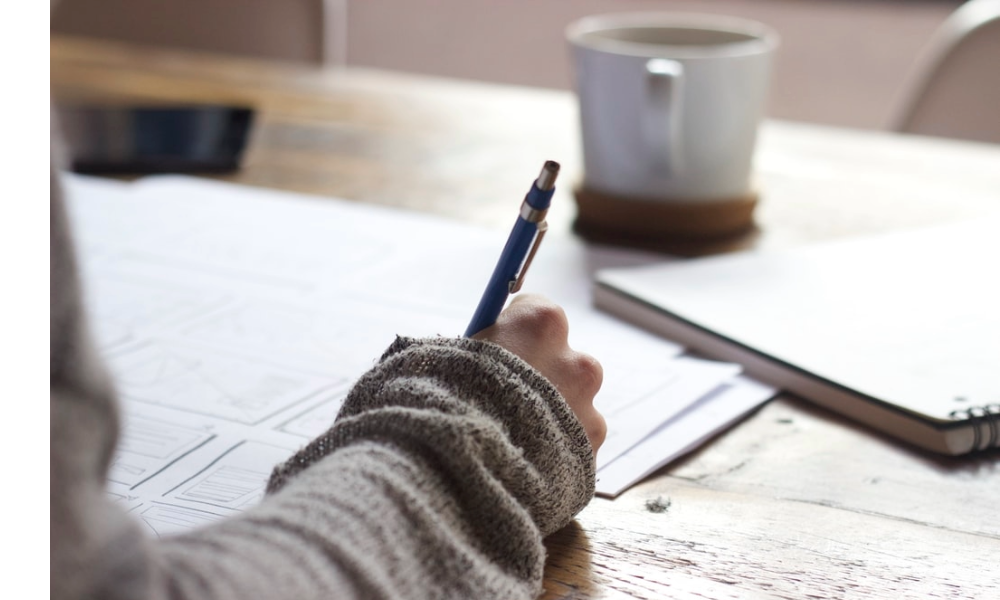 Individual's arm writing on desk.