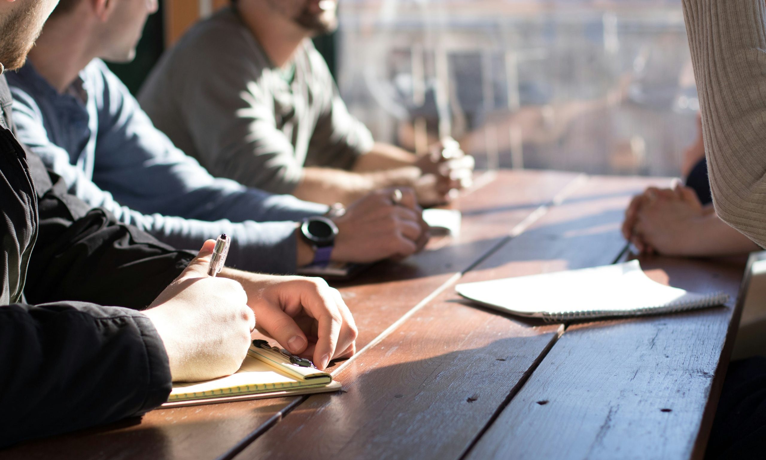 Photo of torsos leaning on tables.