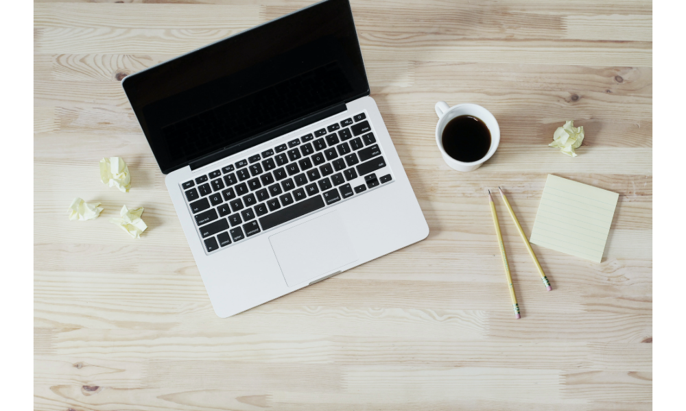 Laptop and black coffe on a tabletop.