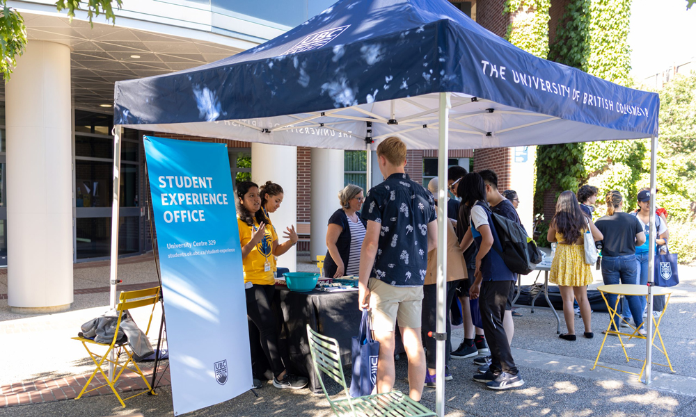 Students conversing outside under the UBCO information tent at Create new student orientation.