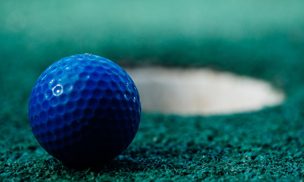 A golf ball next to a hole on the green.