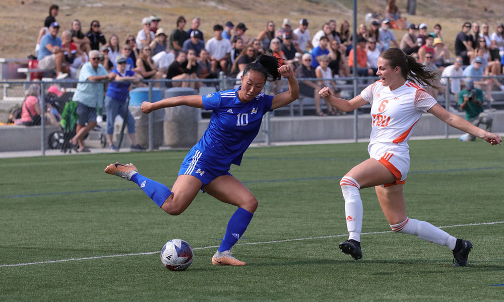 A member of UBC Okanagan's Heat women's soccer team faces off against a member of TRU's team.