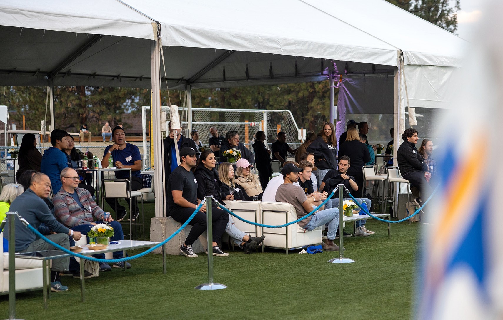 Attendees of Off The Pitch Reception sitting and watching the home coming soccer game.